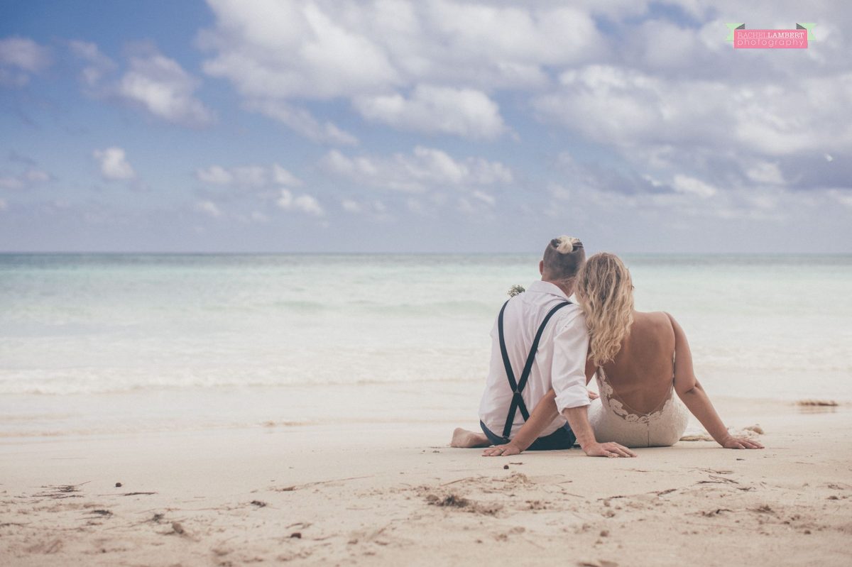 bride and groom sitting on beach in jamaica