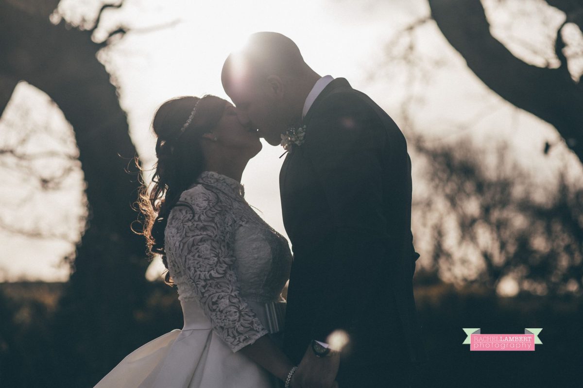 bride and groom kissing sun flare silhouette shot